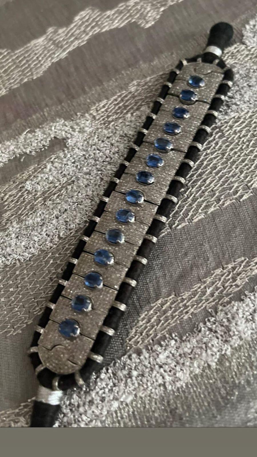 Detailed view of a unique artisan bracelet showcasing lustrous silver, oval blue kyanite gems, and small diamonds, set on a distinct hand-stitched fabric foundation.