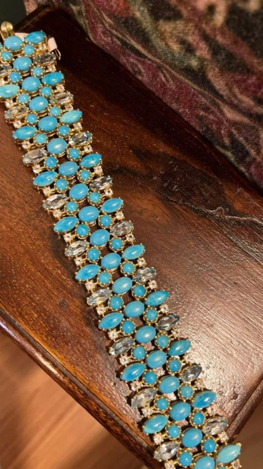 Close-up of a wide sterling silver bracelet densely set with multiple rows of oval and round Persian turquoise cabochons, interspersed with clear, faceted blue aquamarine stones.