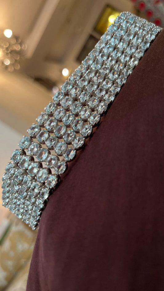 Handcrafted Victorian-style sterling silver bracelet featuring an impressive array of 217 carats of natural blue topaz stones, sparkling on a wrist.


